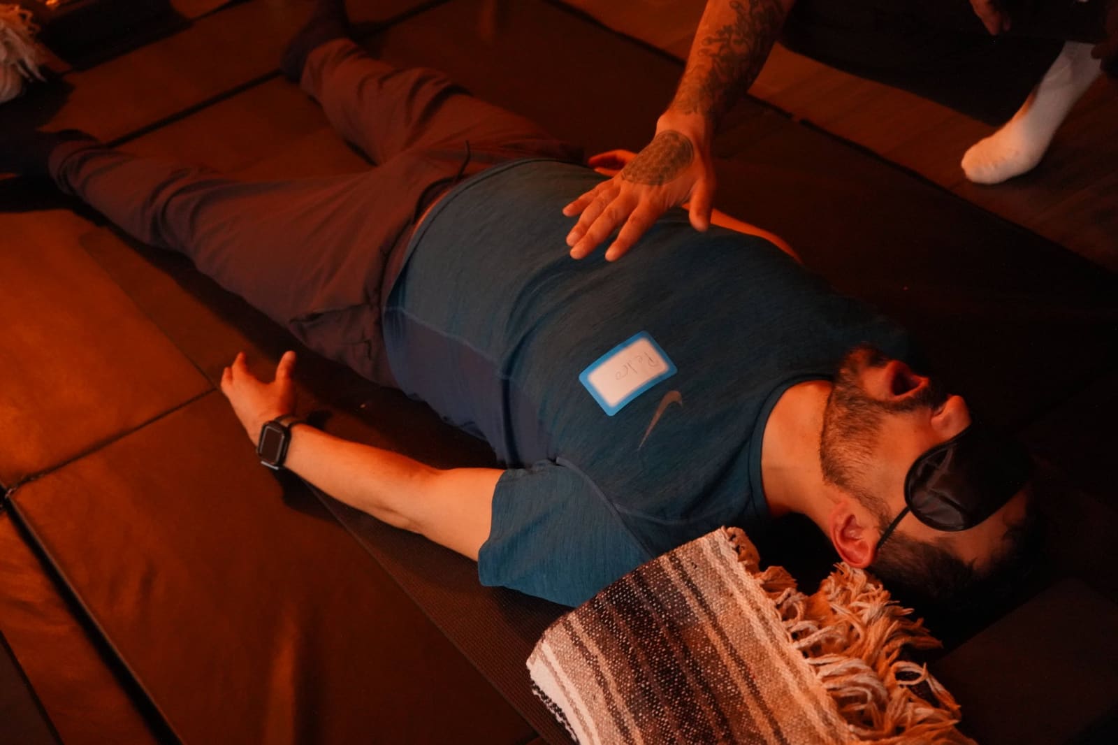 Eddie's tattooed hand guiding a participant during breathwork